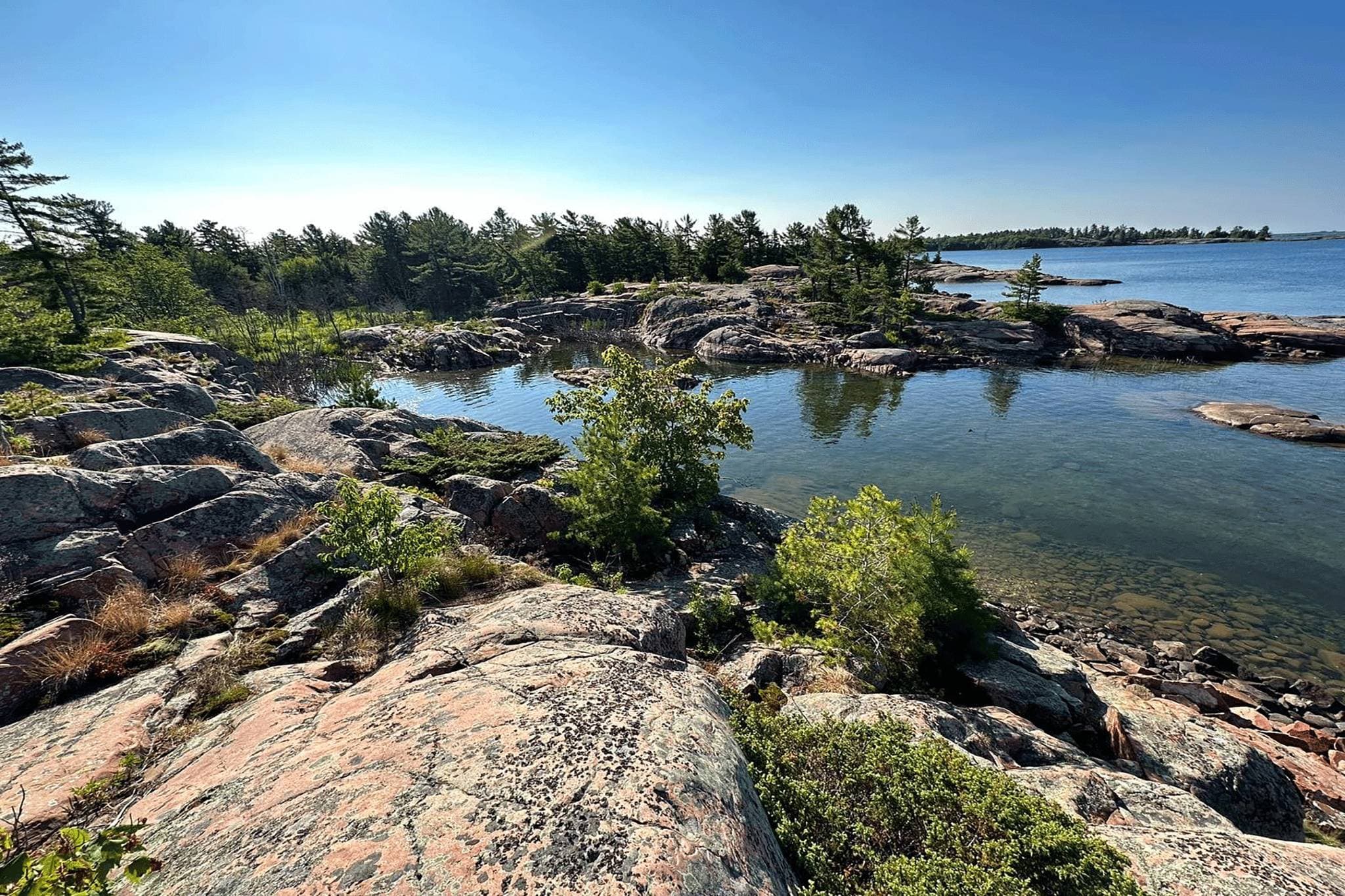 Pink granite shoreline and clear turquoise water on Georgian Bay at Killarney