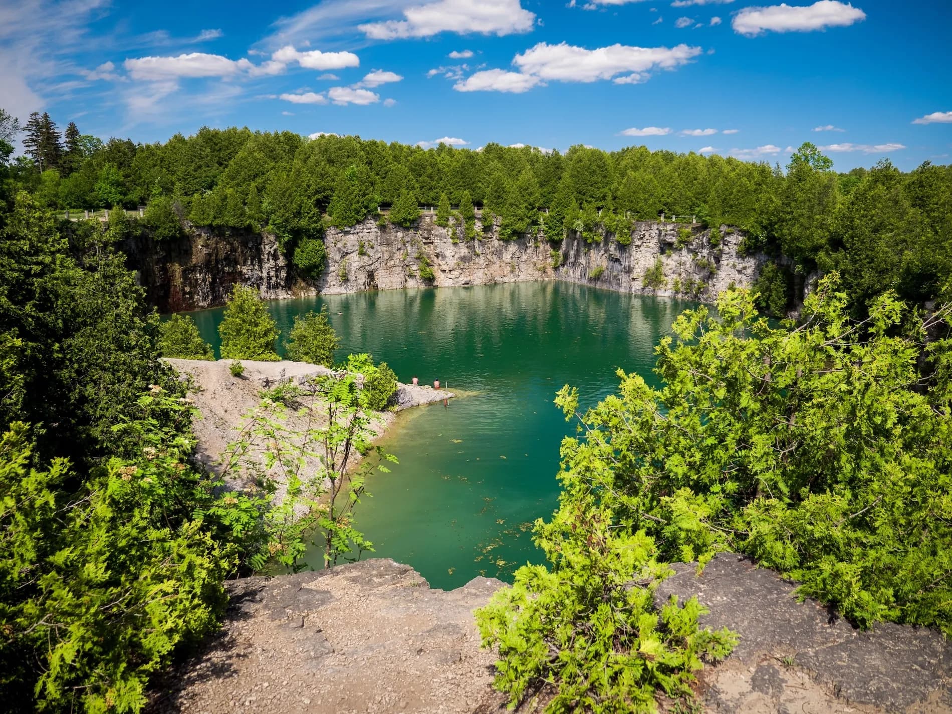 The deep green water of Elora Quarry seen from the limestone rim above it